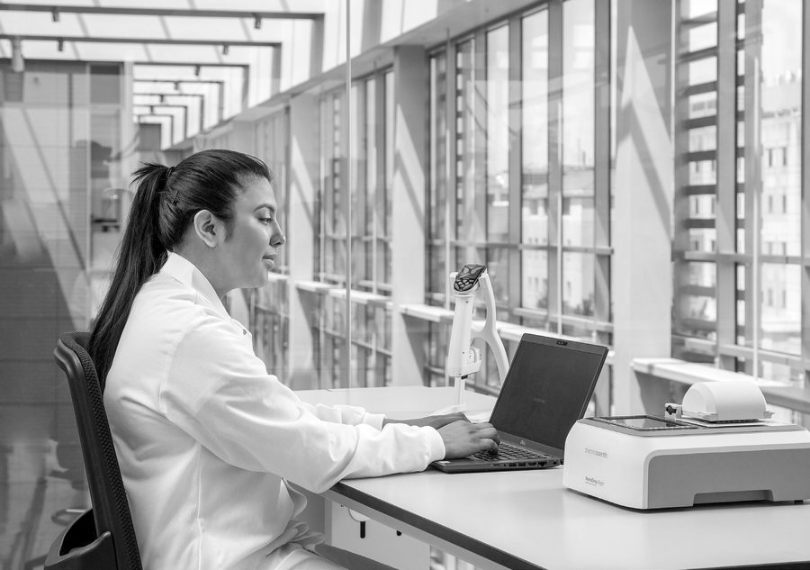Researcher operating NanoDrop Eight with a computer for compliant workflows